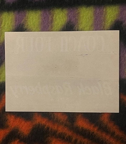 Blank cream-colored label or paper displayed on striped fabric background in shades of yellow, purple, and orange