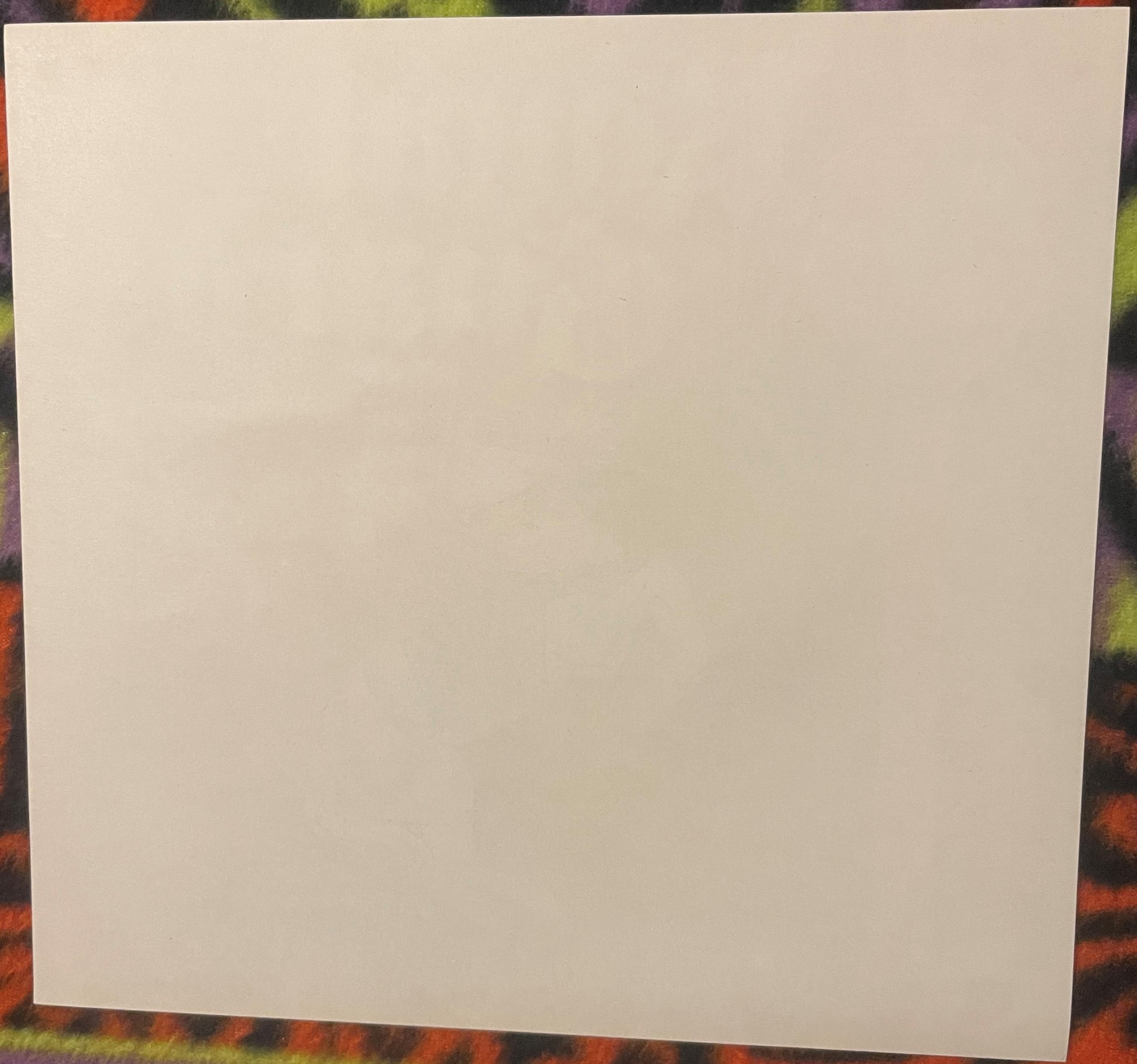 Blank cream-colored paper or card displayed against a colorful patterned background