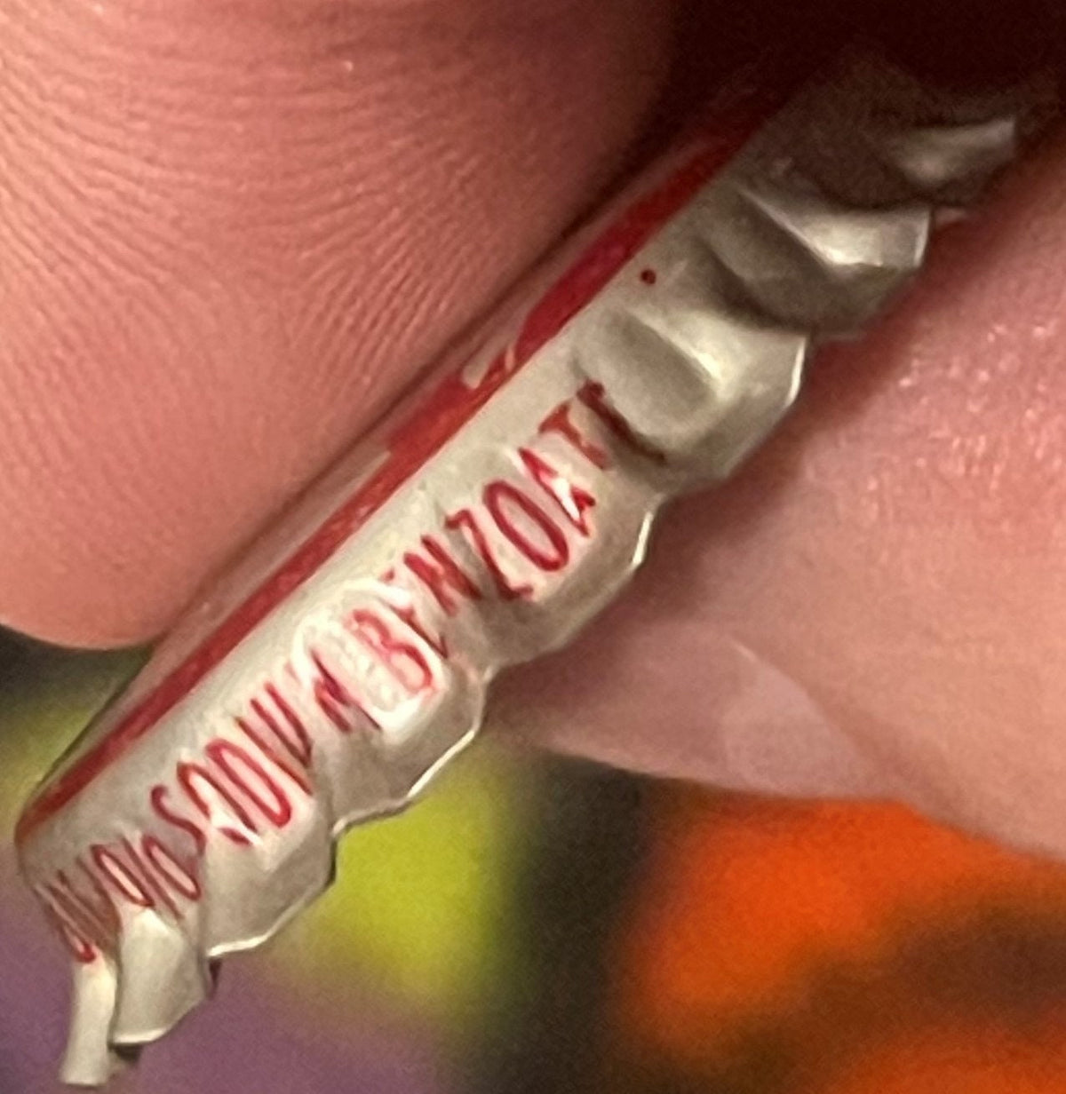 Vintage Cherry Smash bottle cap held against skin for scale, showing red and white label text, close-up detail view