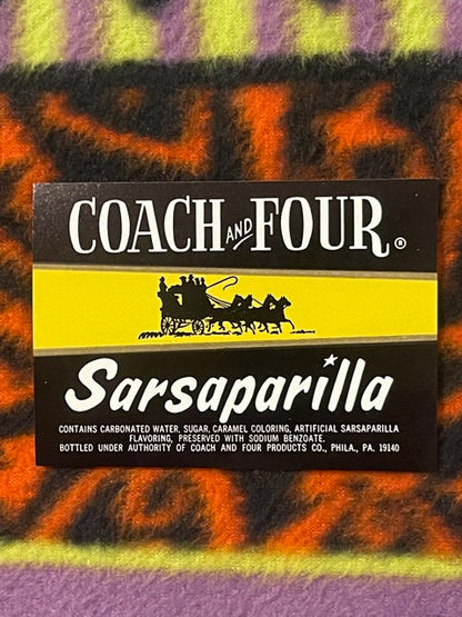 Vintage Coach and Four Sarsaparilla soda label on colorful striped fabric background, showing black banner with horse-drawn c