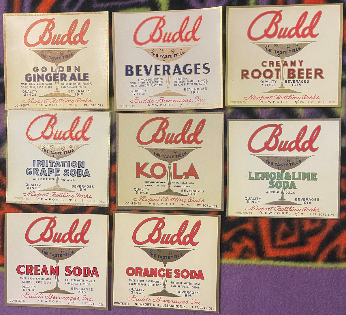 Eight vintage Budd soda bottle labels from Newport Bottling Works arranged in a grid, featuring red script logo and flavors i