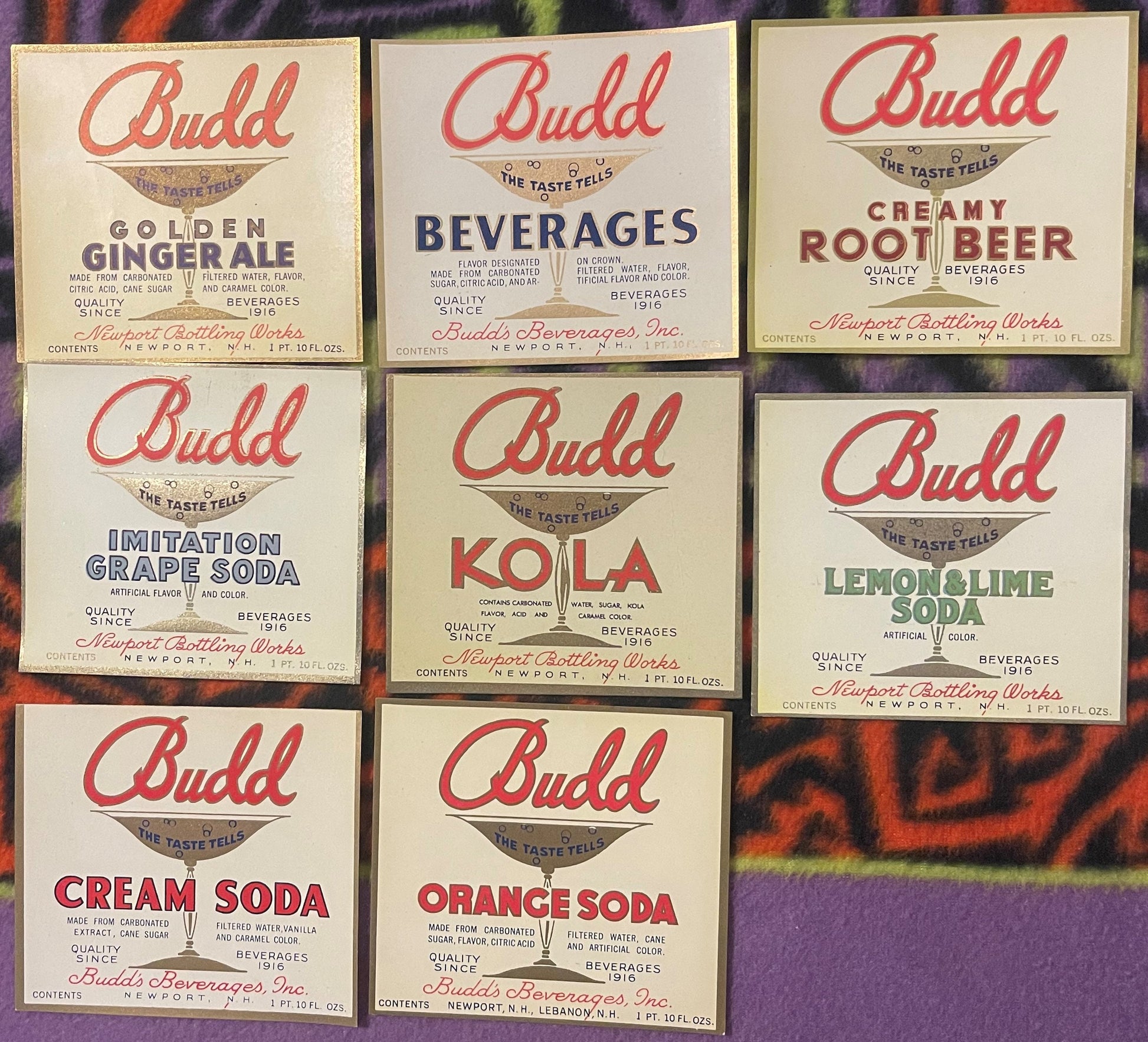 Eight vintage Budd soda bottle labels from Newport Bottling Works arranged in a grid, featuring red script logo and flavors i