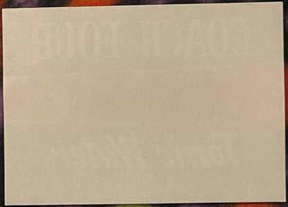 Blank cream-colored rectangular label or paper sample against a dark patterned background