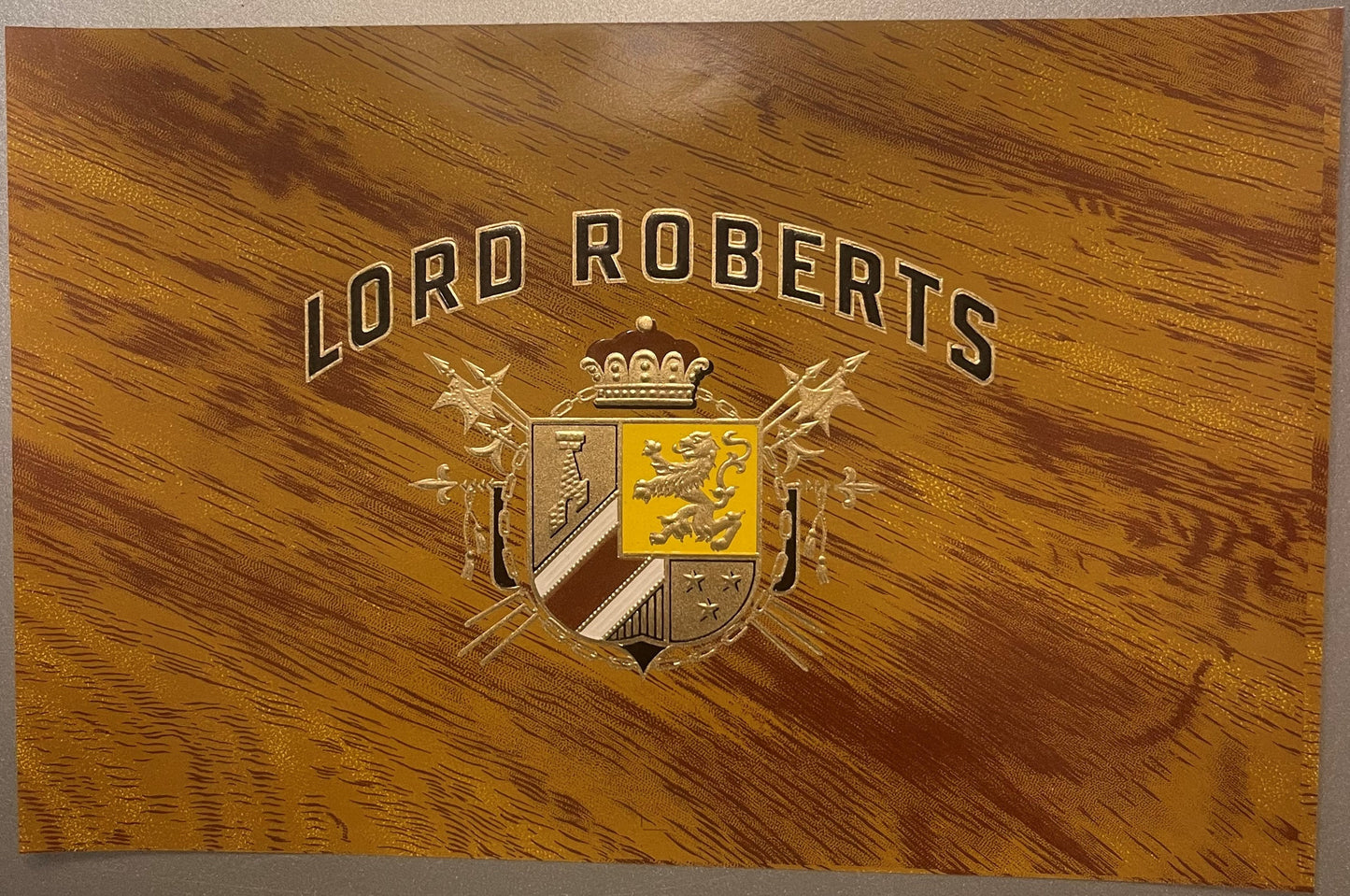 Gold embossed cigar label with "LORD ROBERTS" text, heraldic coat of arms with crown, and wood grain background texture