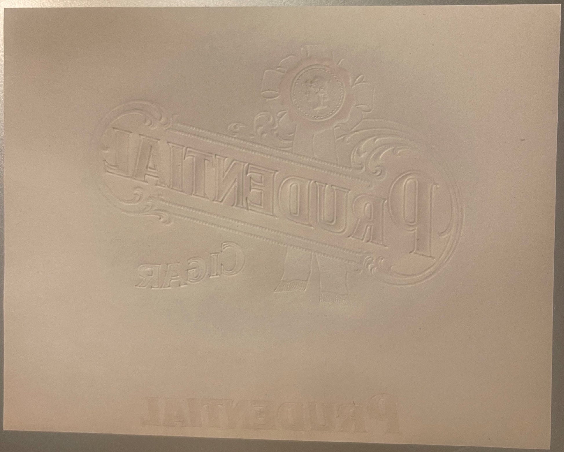 Embossed cream-colored cigar label with ornate decorative border, coins, and scrollwork, featuring "PRUDENTIAL" text in relie