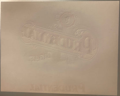 Embossed cream-colored cigar label with ornate decorative border, coins, and scrollwork, featuring "PRUDENTIAL" text in relie