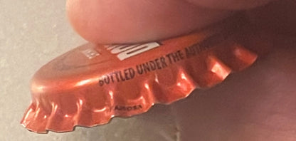 Vintage red Double Cola bottle cap with ridged edges, held in a hand, showing embossed text on the crown