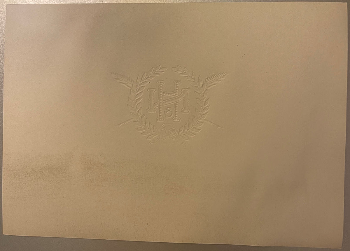Back of the N&H cigar label: plain cream paper with the monogram, wreath and crossed shafts embossed in reverse