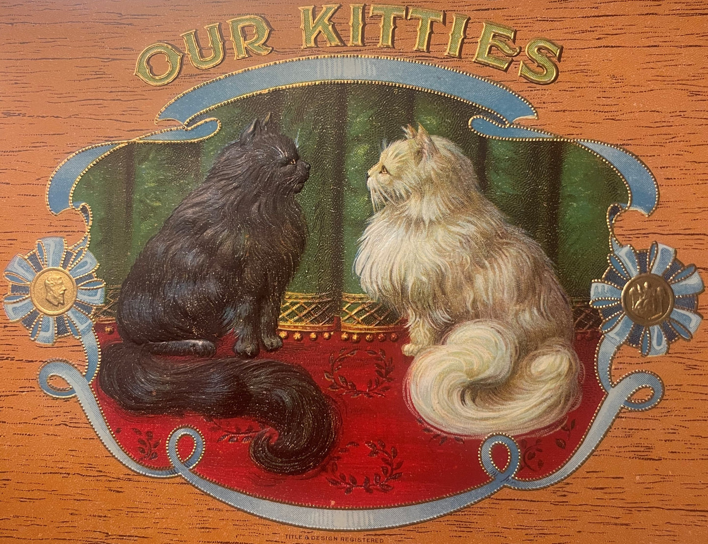 Gold-embossed chromolithograph cigar box label featuring two long-haired cats on red and green background with "OUR KITTIES" 