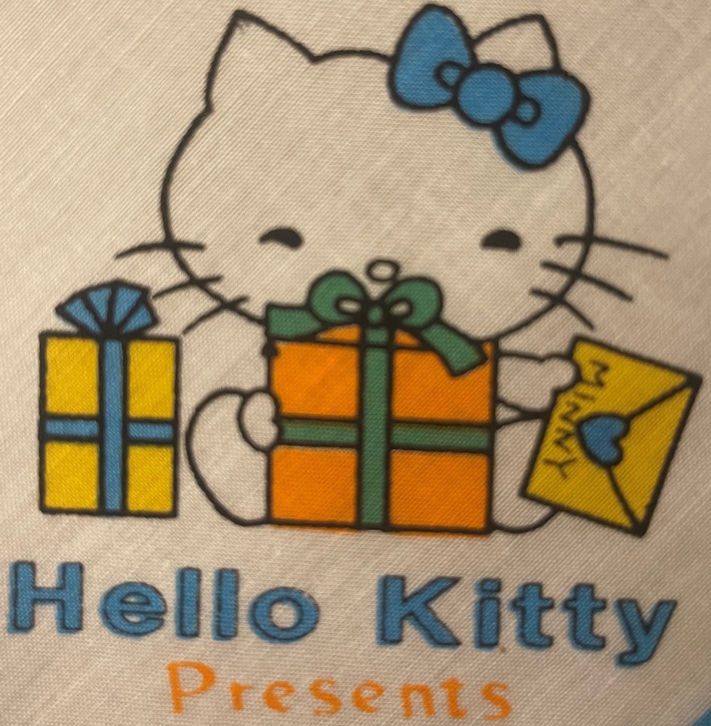 Vintage Hello Kitty cotton napkin with blue bow, holding colorful presents, printed text "Hello Kitty Presents" on cream fabr