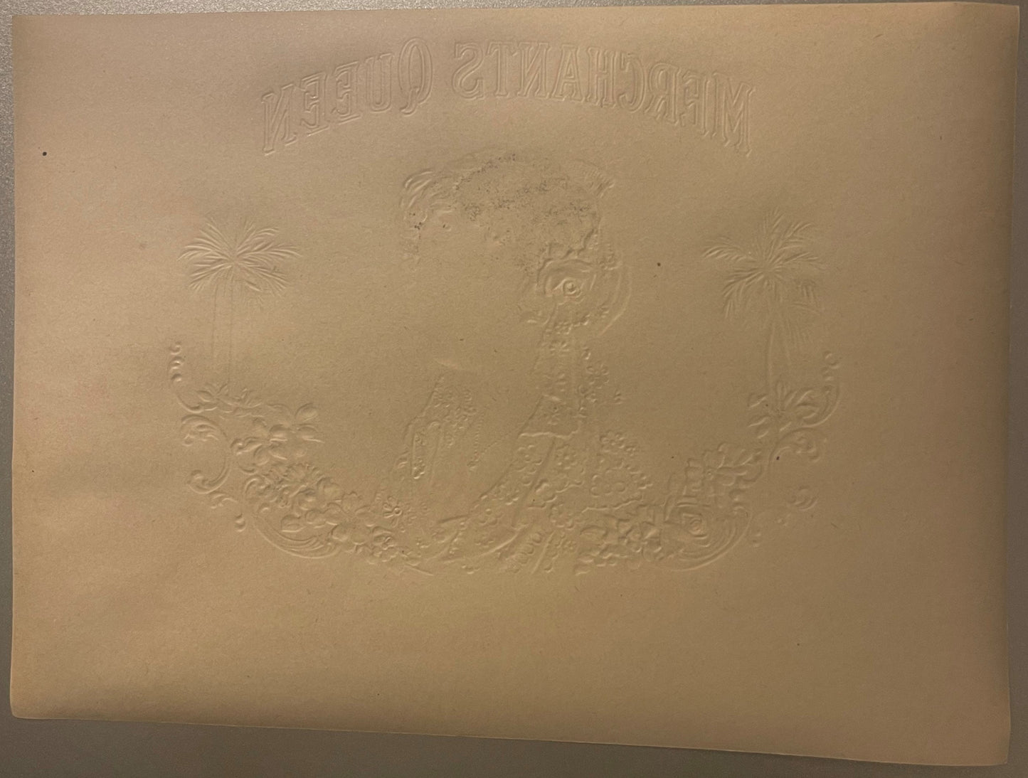 Embossed cream-colored cigar label featuring a woman's portrait, palm trees, and ornamental scrollwork, with reversed text at