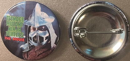 Front and back of a circular pinback button featuring Shredder from Teenage Mutant Ninja Turtles The Movie, with green text l