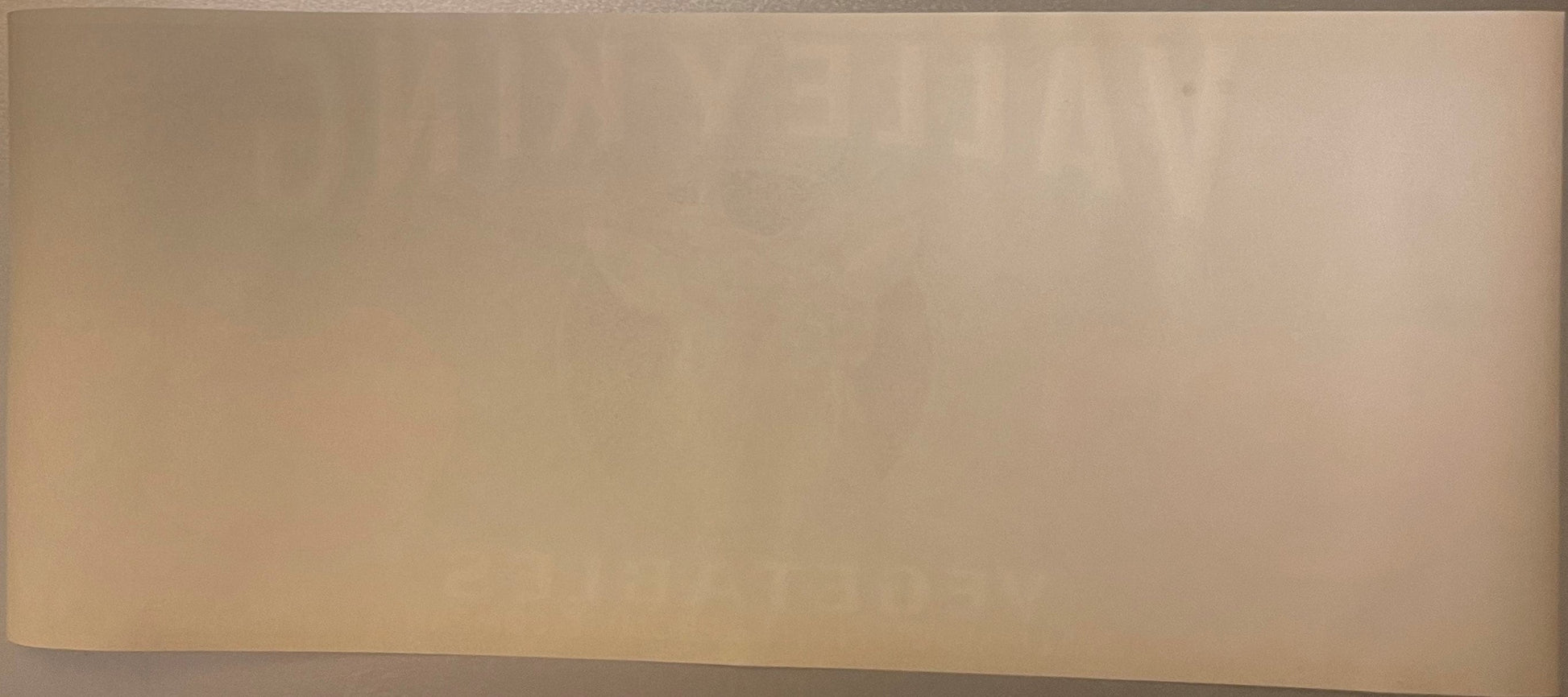 Cream-colored vintage vegetable crate label with faded printing, photographed flat against neutral background