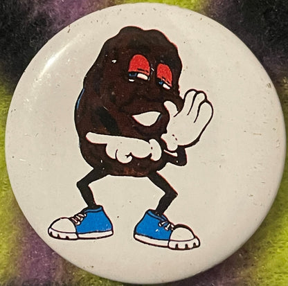 Vintage California Raisin tin pin featuring a cartoon character with dark body, red sunglasses, white gloved hands, and blue 