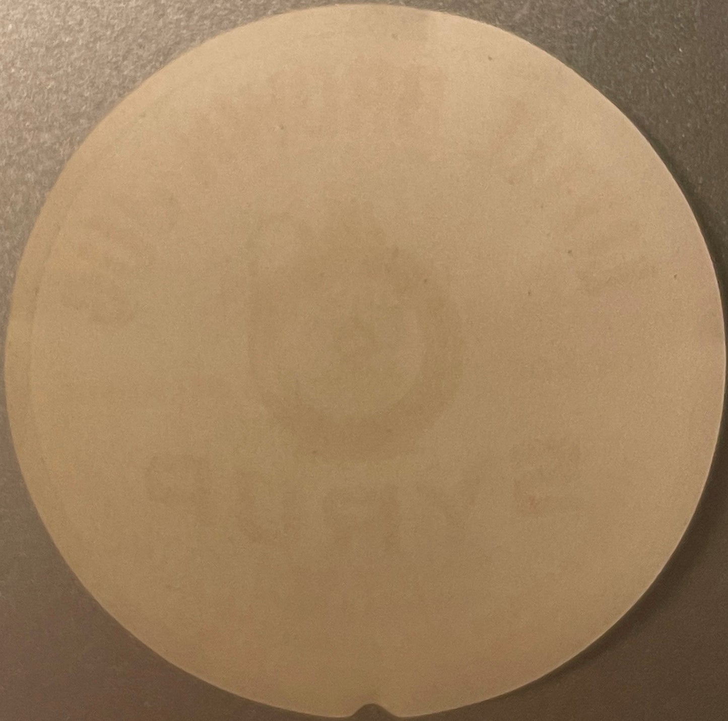 Blank cream-colored circular label on gray surface, viewed from above