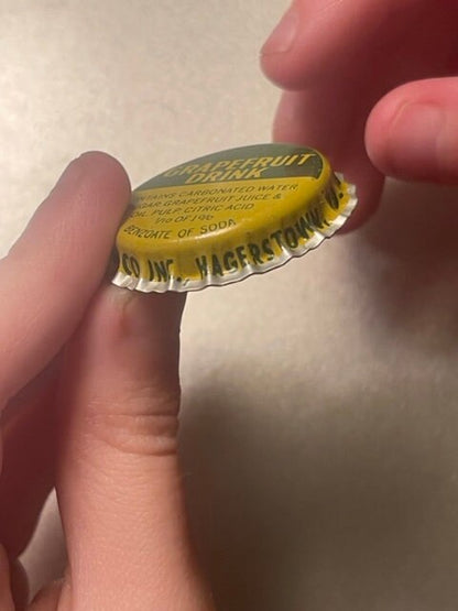 Yellow vintage bottle cap held in hand, printed with "Seven-Up" and "Hagerstown MD" text, shown at close angle for detail