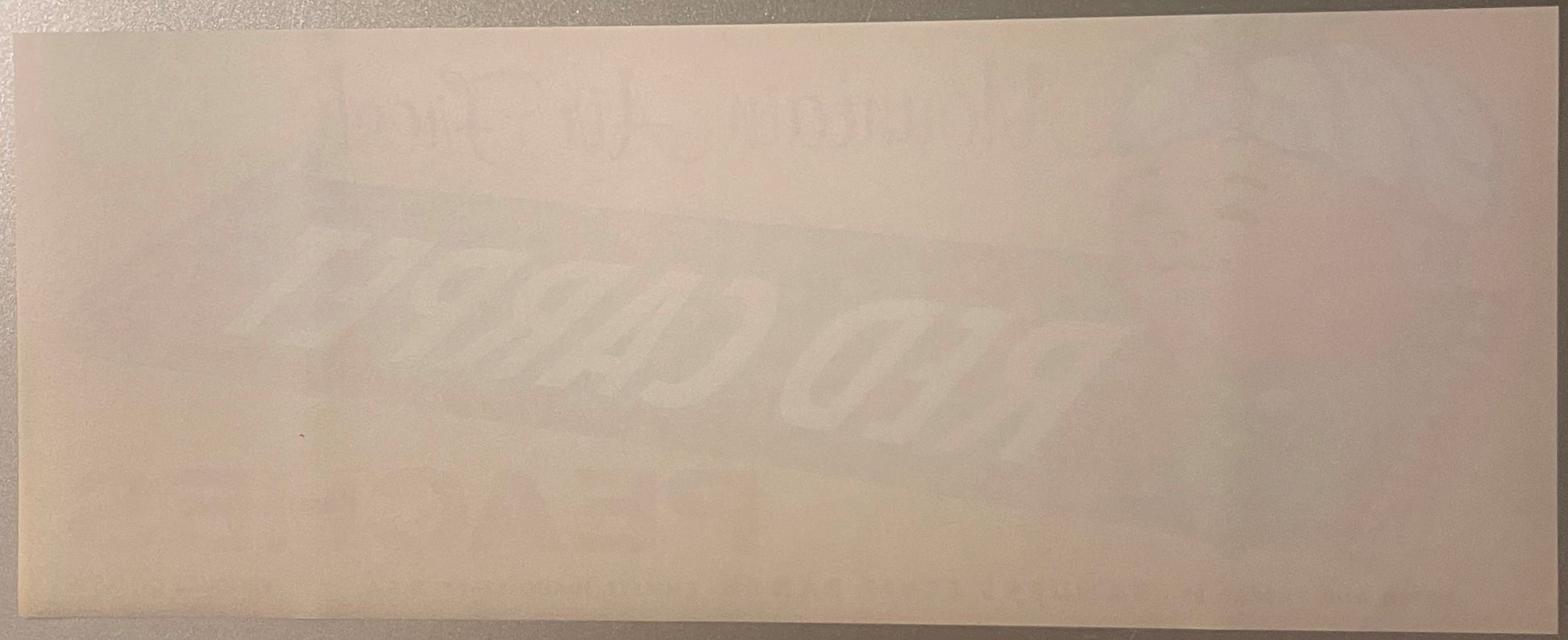 Blank peach crate label with faint watermark text visible against beige background, photographed flat