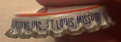 Close-up of vintage cork-lined bottle cap with "...PRODUCTIONS, INC., ST. LOUIS, MISSOURI" text, red stripe and decorative scalloped edge