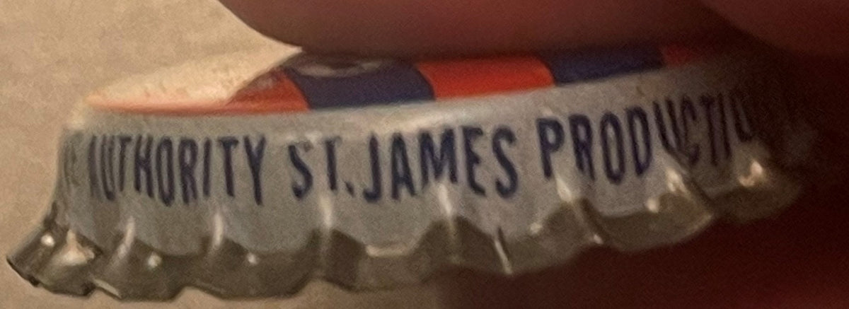 Side of a bottle cap held under a finger, with blue text reading 'Authority St. James Productio...' above the scalloped edge.