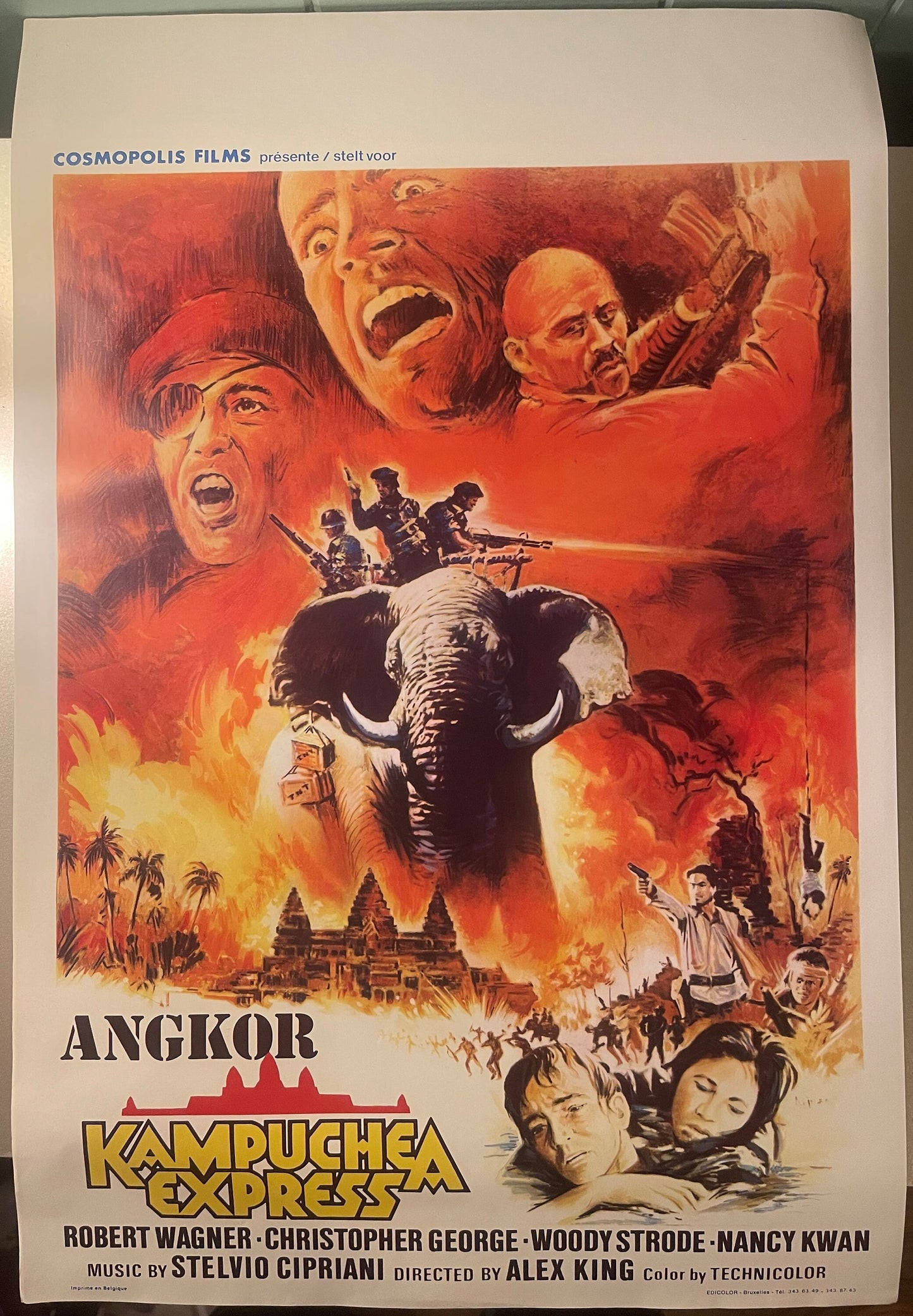 Vintage movie poster featuring a large elephant with armed soldiers, fiery explosions, and dramatic character portraits in re