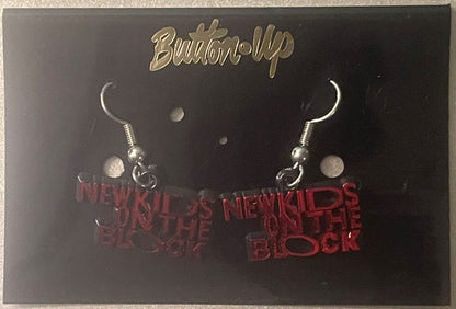 Pair of silver-toned dangle earrings with red "New Kids on the Block" text charms on black display card with gold "Built-Up" 