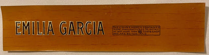 Wooden cigar box lid with embossed "EMILIA GARCIA" lettering and tax stamp information on brown wood background.