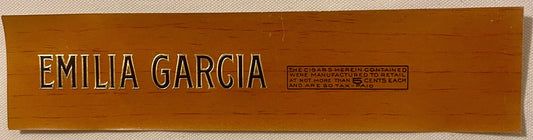Wooden cigar box lid with embossed "EMILIA GARCIA" lettering and tax stamp information on brown wood background.
