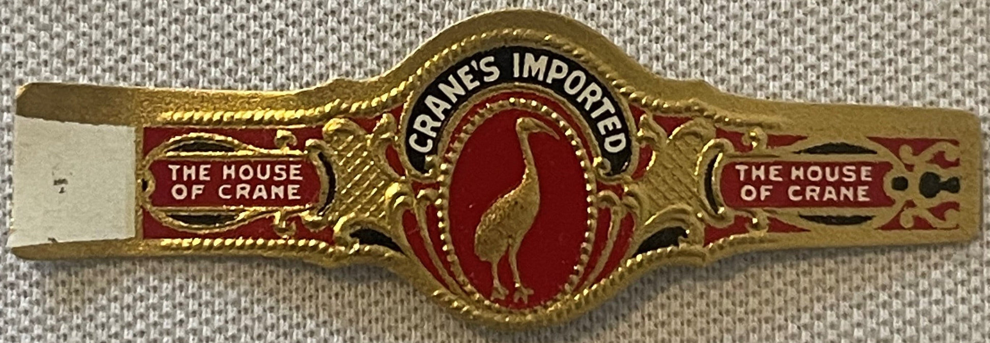 Gold-embossed cigar band with red enamel center featuring a crane, "The House of Crane" text on sides, "Cranes Imported" at t