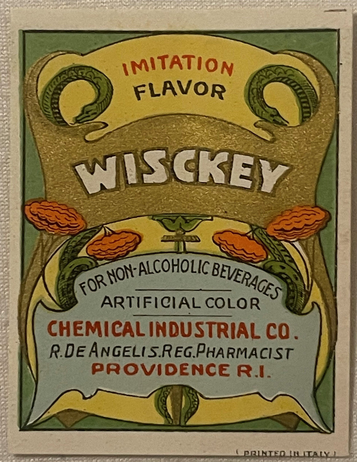 Vintage "Wisckey" whiskey flavor label with art deco design featuring serpents, pinecones, and gold lettering on green