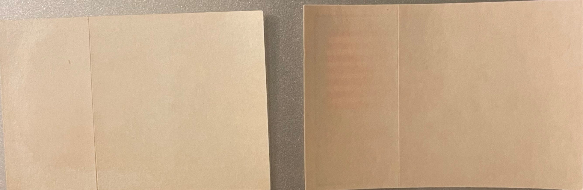 Two unopened vintage sticker packages with cream and tan cardboard sleeves, photographed from above on a gray surface