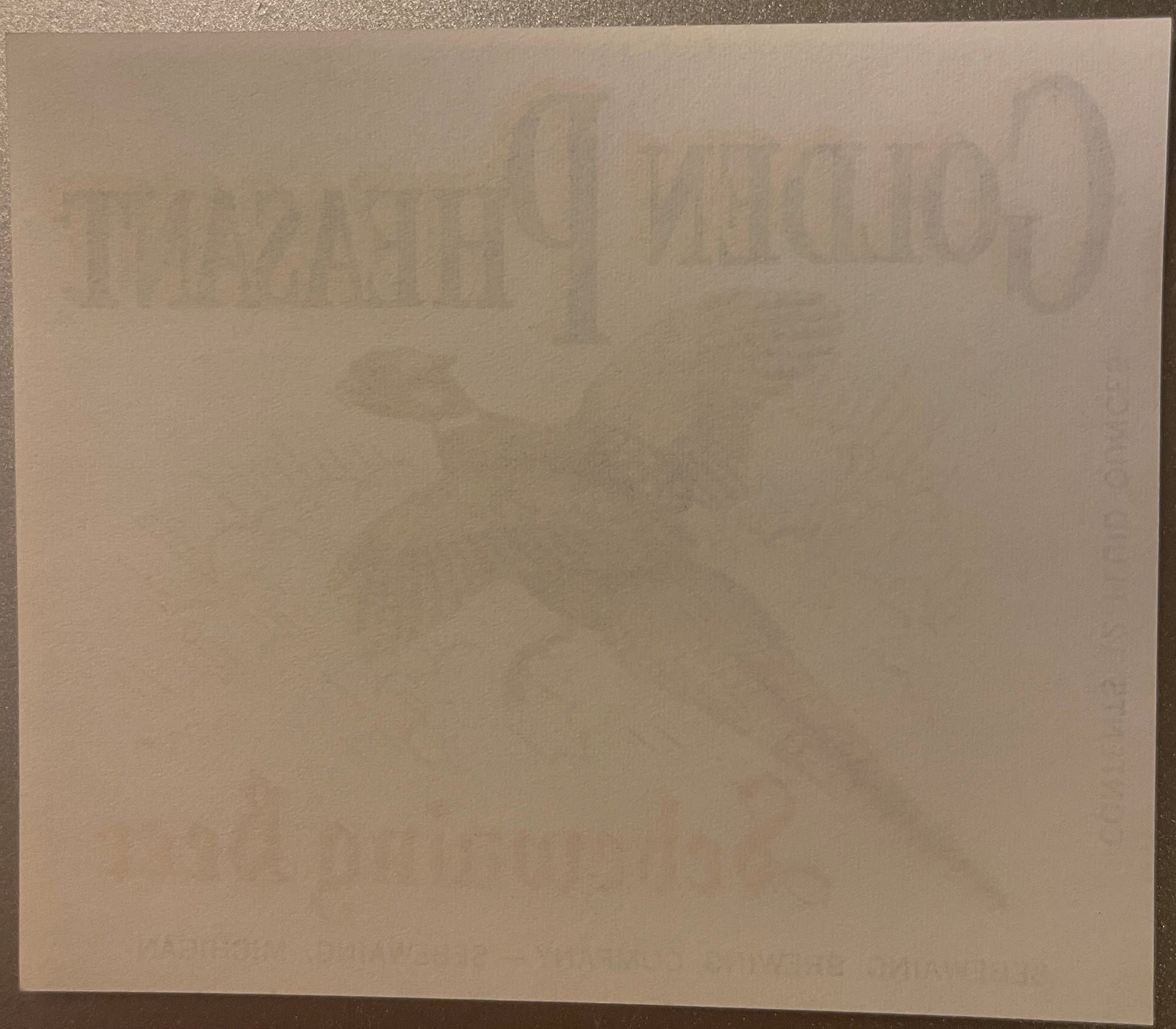 Faded vintage beer label with embossed Golden Pheasant branding and Michigan brewery text, displayed on cream paper against d