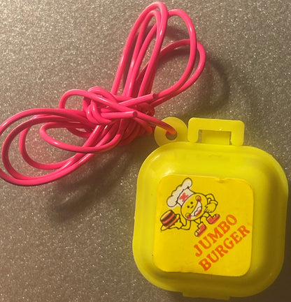 Yellow Jumbo Burger charm box on a hot pink cord, lid label showing a cartoon chef in a white hat carrying a hamburger