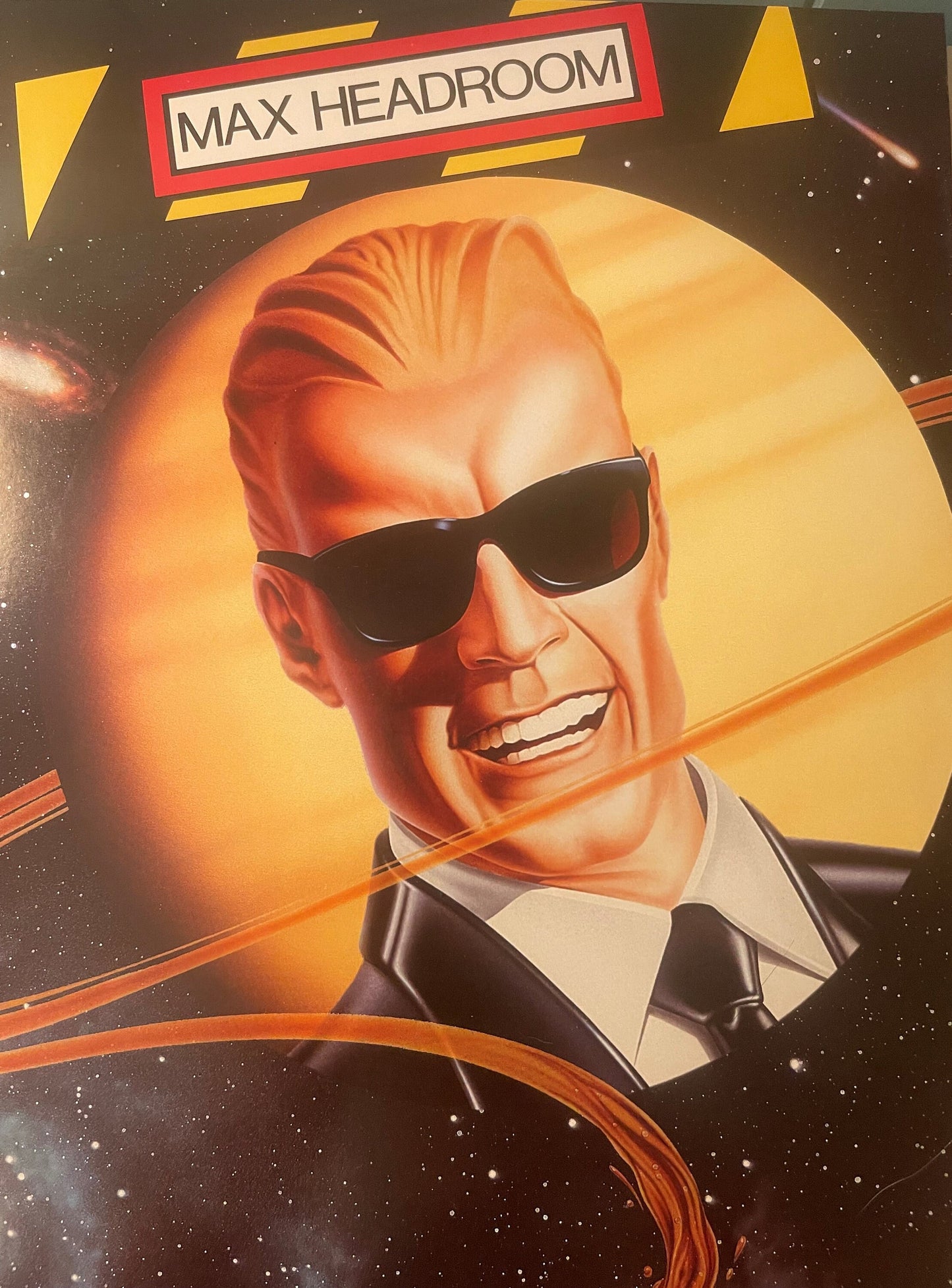 Vintage Max Headroom poster featuring illustrated man in sunglasses and suit against glowing orange sun with space theme, red