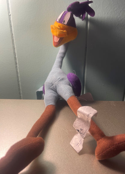 Vintage Road Runner plush toy displayed on table with attached care tag, showing purple head, orange beak, gray body, orange 