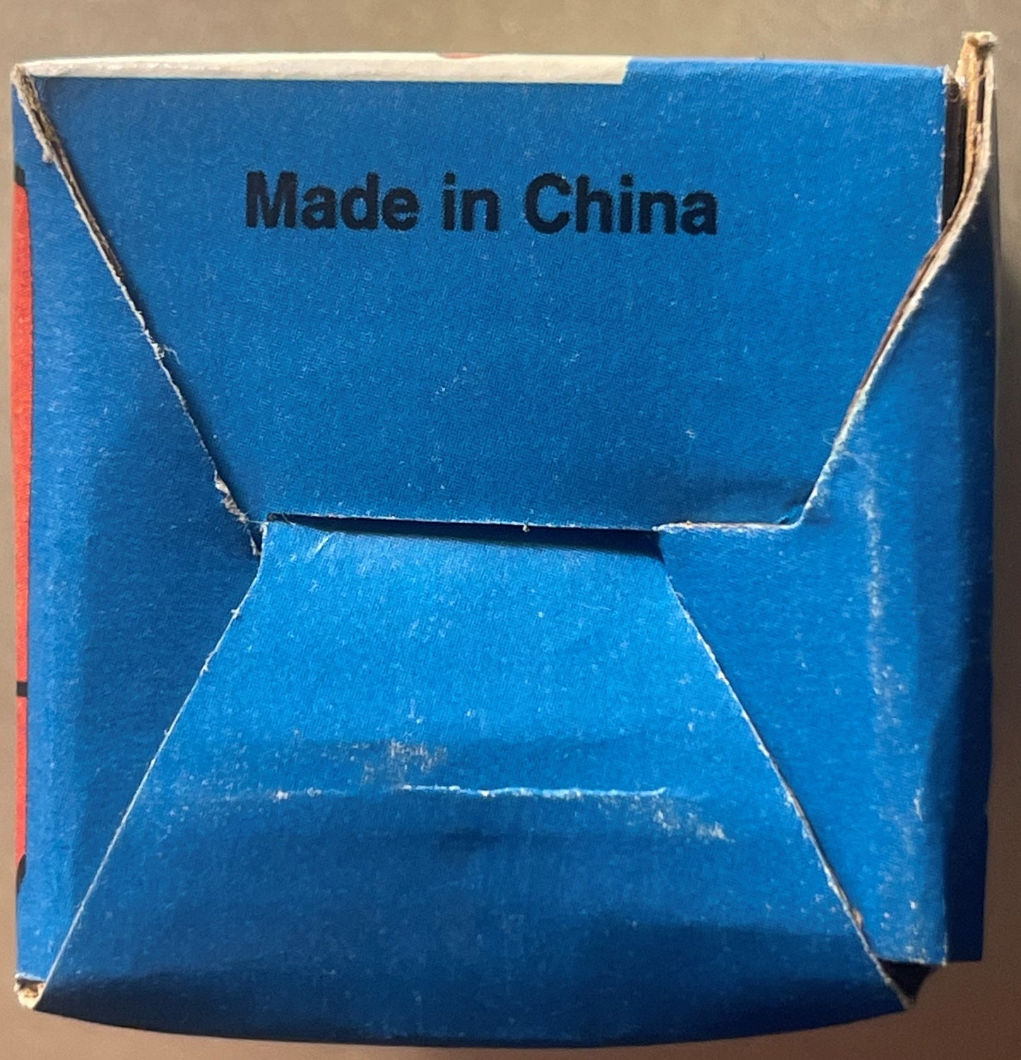 Blue cardboard box with "Made in China" printed in black text, showing worn edges and flap openings