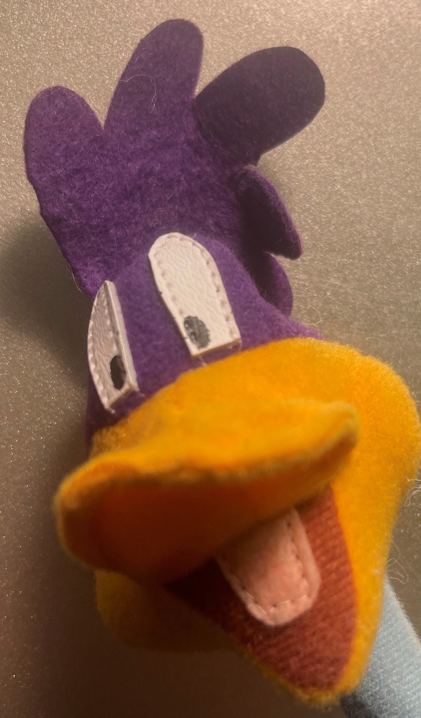 Vintage Road Runner plush toy shown from above, displaying purple head with white eyes and yellow-orange body with open beak,
