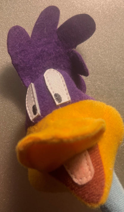 Vintage Road Runner plush toy shown from above, displaying purple head with white eyes and yellow-orange body with open beak,