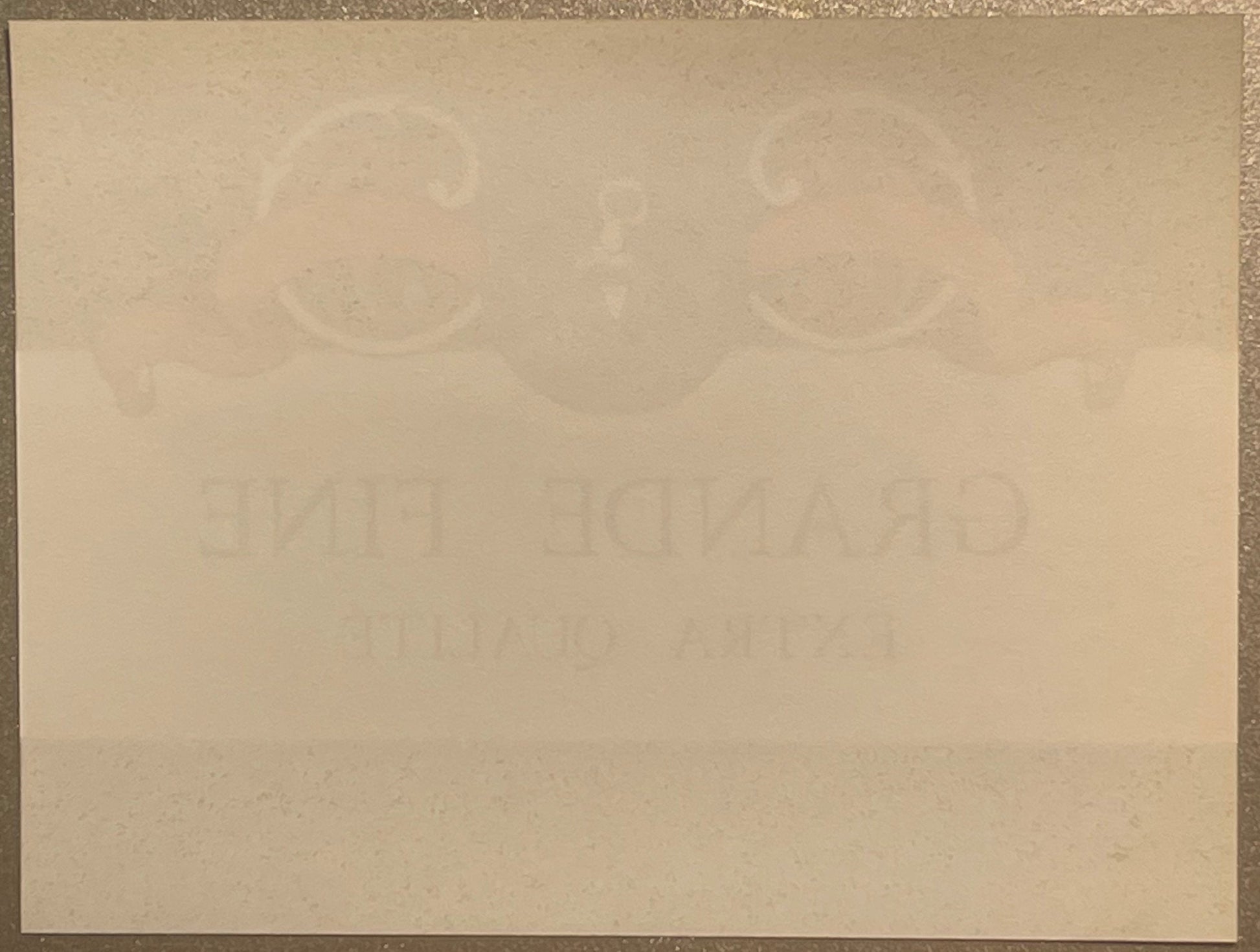 Faded cream-colored vintage wine label with embossed circular designs at top and partially visible text, photographed flat ag