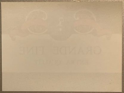 Faded cream-colored vintage wine label with embossed circular designs at top and partially visible text, photographed flat ag