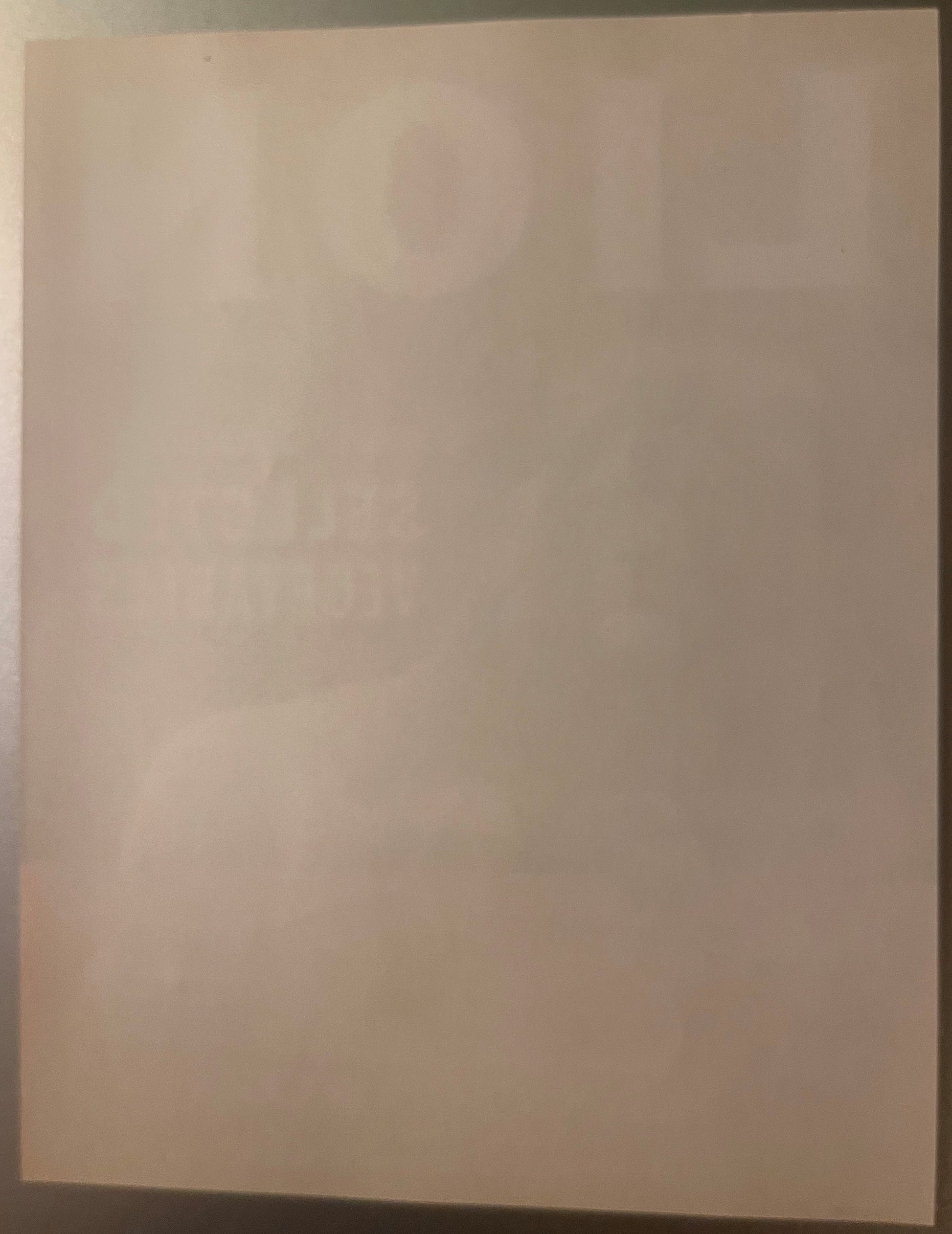 Blank cream-colored vintage crate label photographed at an angle against a dark surface, showing wear and discoloration consi