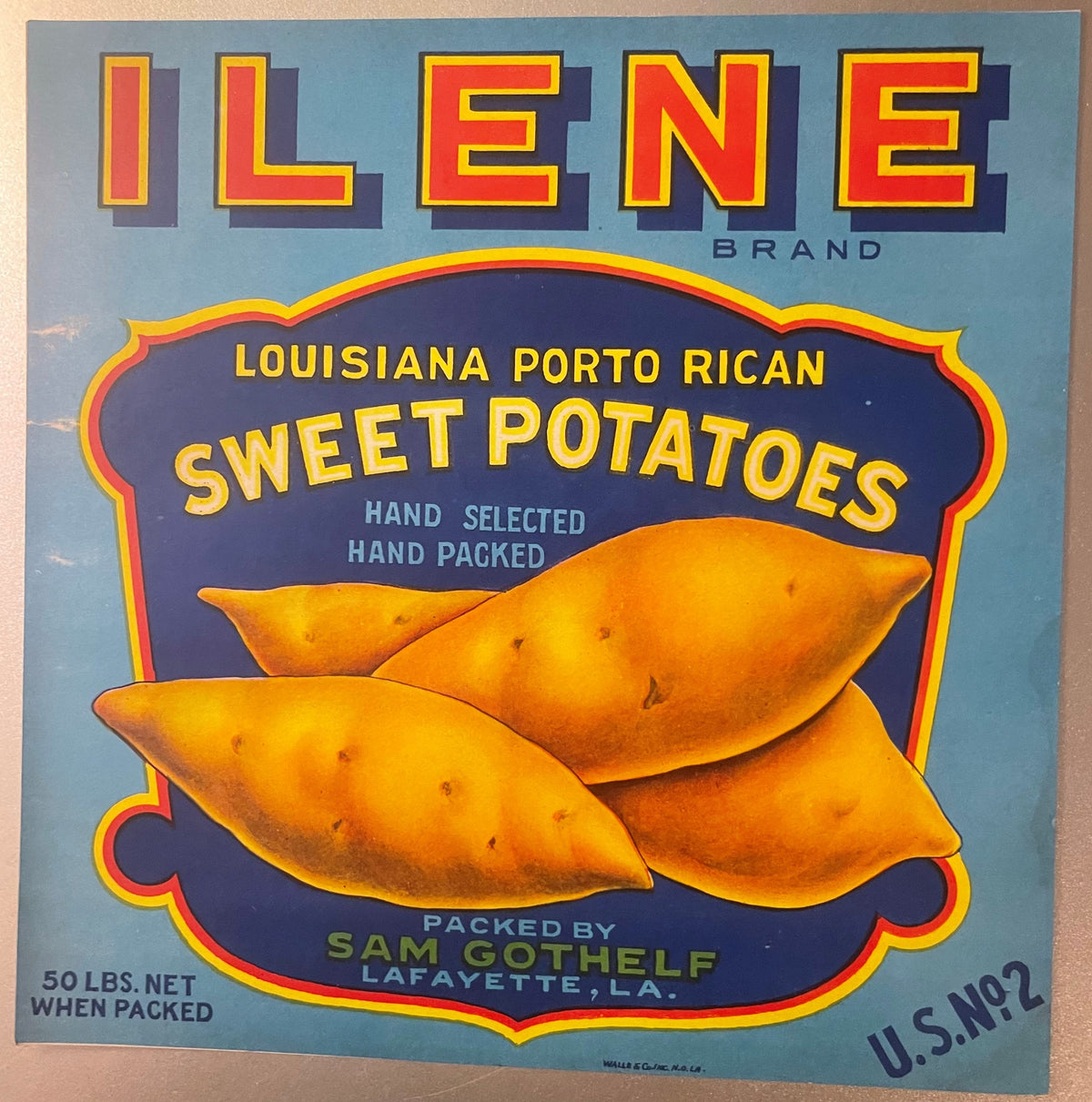 Vintage Ilene Brand sweet potato crate label with three orange yams on dark blue shield, yellow and red text, light blue back