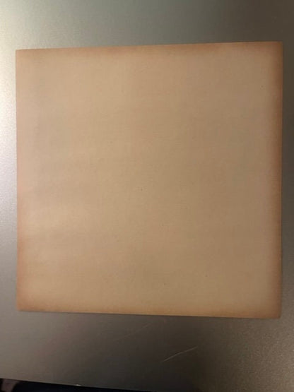 Blank peach-colored vintage crate label mounted on white wall, photographed straight-on