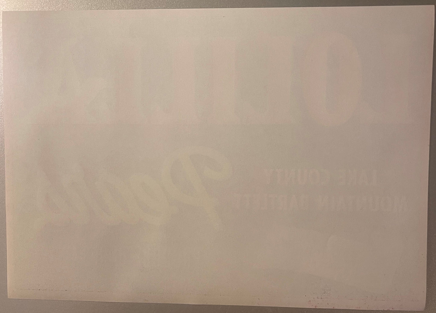 Cream-colored vintage fruit crate label with faint watermark or design, photographed at an angle against neutral background