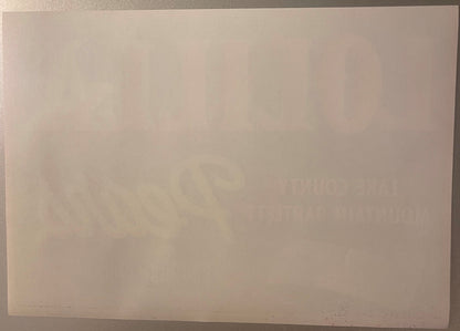 Cream-colored vintage fruit crate label with faint watermark or design, photographed at an angle against neutral background
