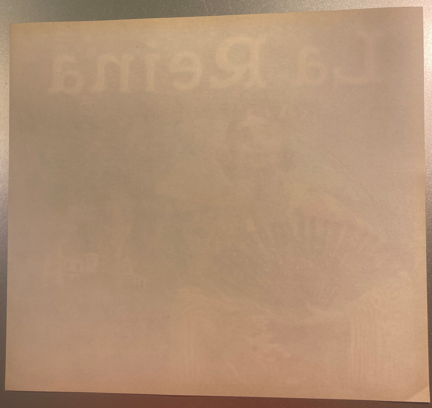 Cream-colored vintage orange crate label with faint embossed or printed text, displayed flat on a beige surface for documenta