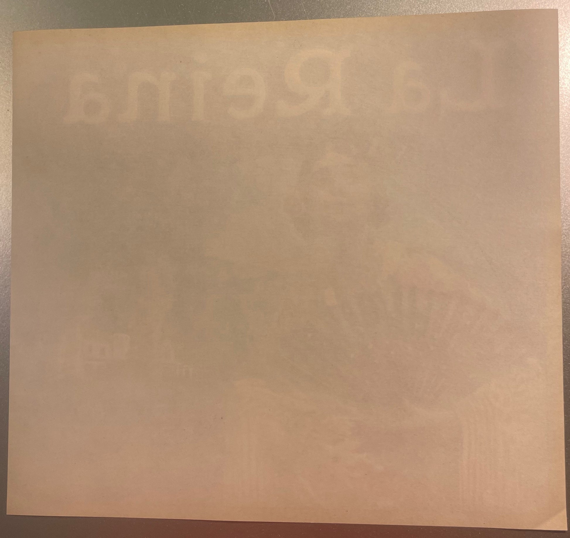 Cream-colored vintage orange crate label with faint embossed or printed text, displayed flat on a beige surface for documenta