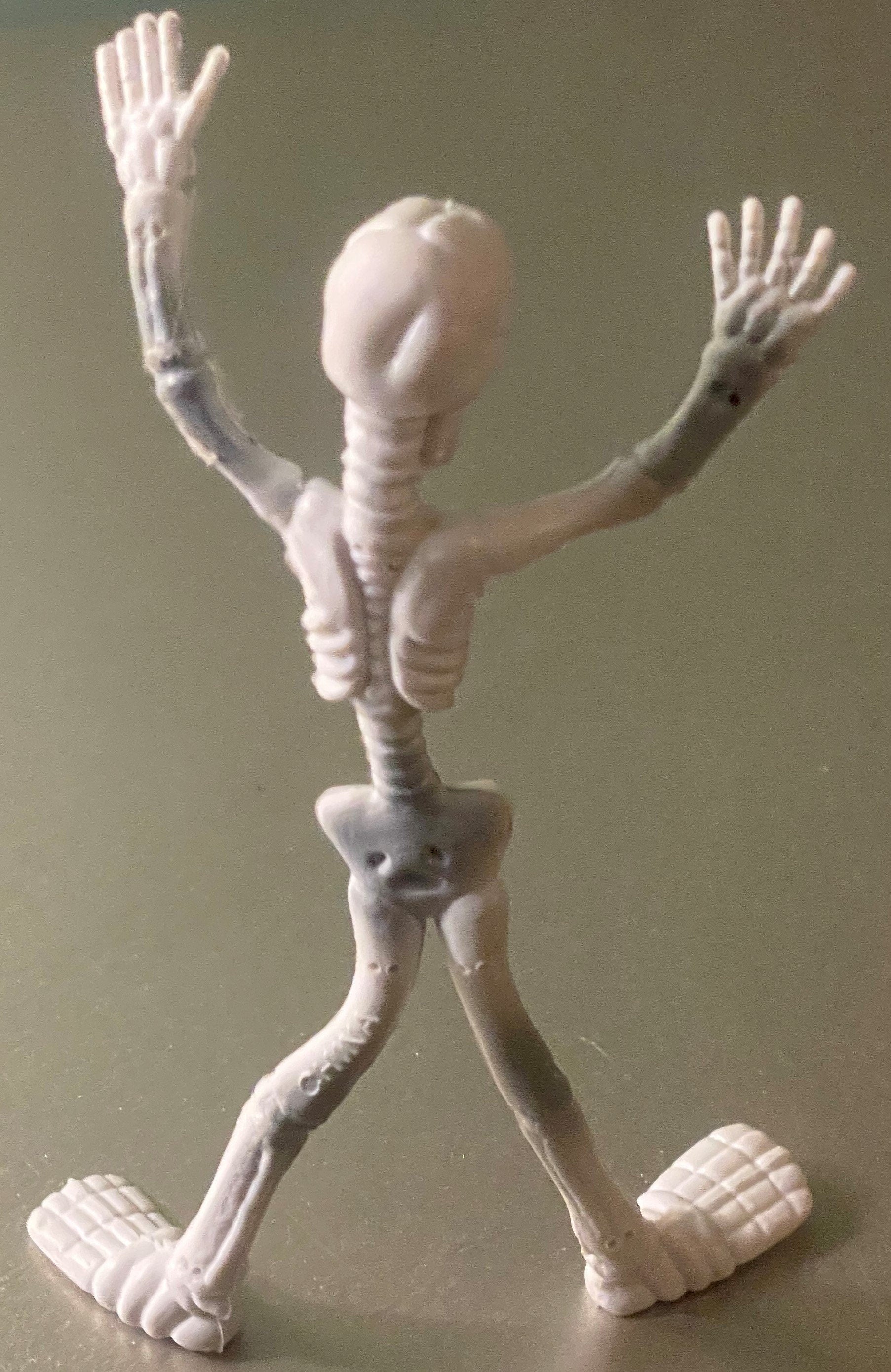 White poseable skeleton figure with articulated limbs and joints, arms raised, standing against neutral background