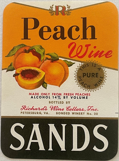 Sands Peach Wine label: two whole peaches and one halved peach with a red-brown stone, orange upper field cut by a gold diagonal into white. Peach in brown serif, Wine in red script, SANDS in white on a black foot band.