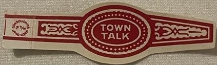 Burgundy and cream cigar band with "Town Talk" text in oval center, decorative geometric borders, laid flat on beige fabric