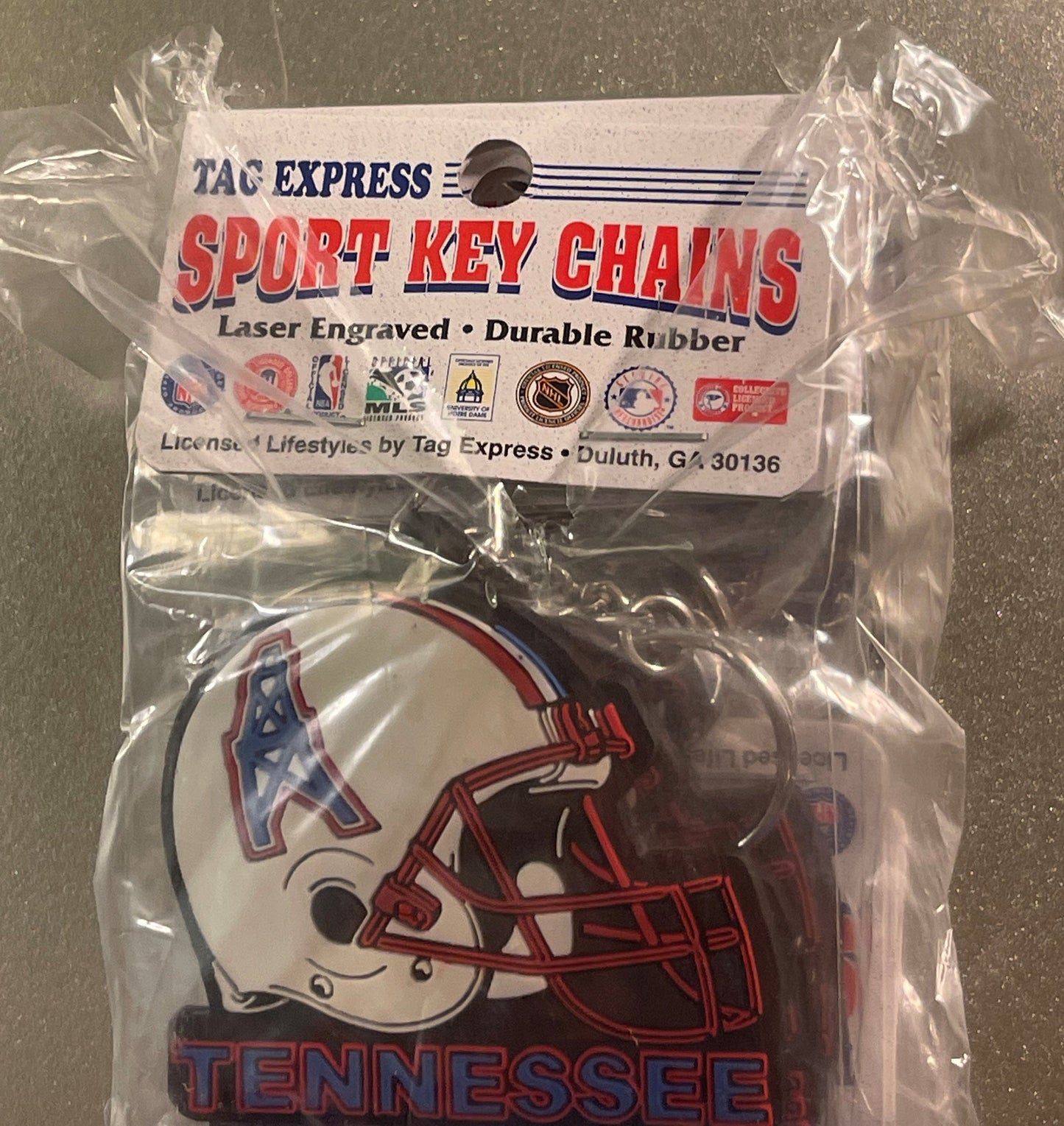 Sealed plastic package containing a white and red Tennessee Oilers NFL helmet keychain with "TENNESSEE" text, Tag Express Spo